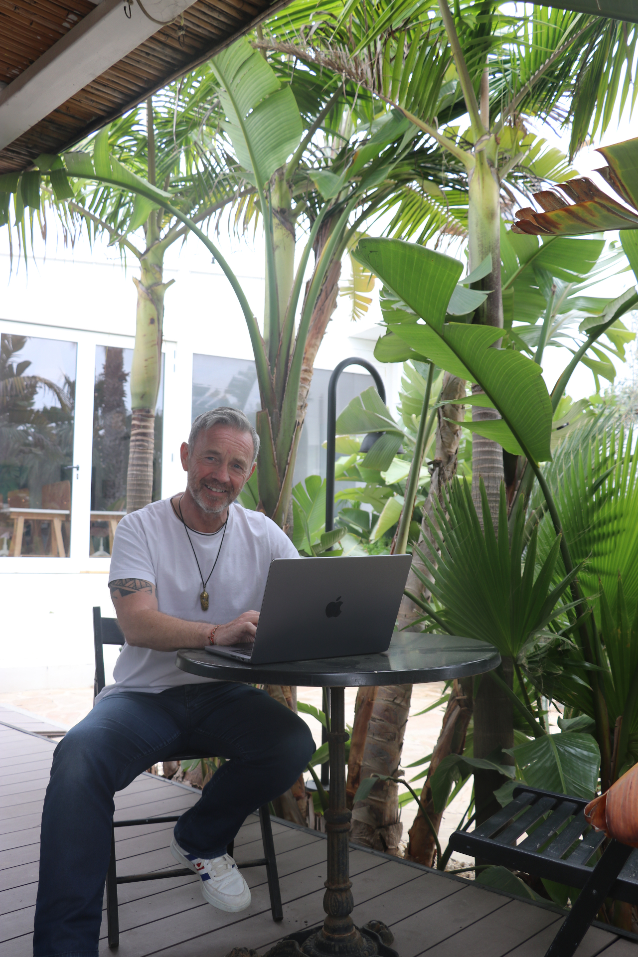 Davie Gowans working from a palm-shaded terrace in Ibiza
